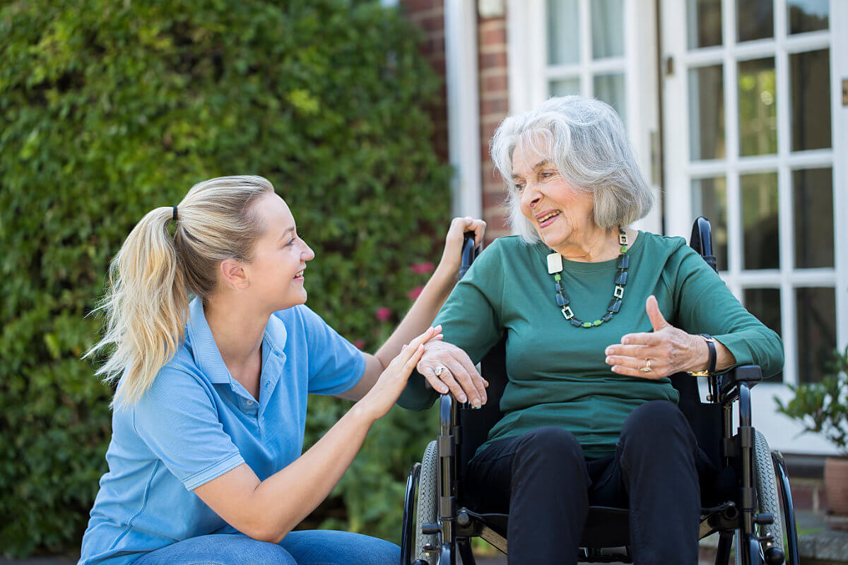 Female nurse talking with an elderly woman in a wheel chair at an assisted living facility