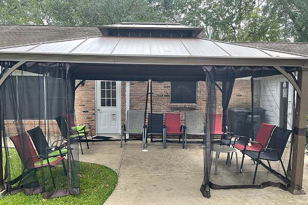 Covered back yard patio with screening and chairs at Park Forest Drive, an assisted living facility located in Cypress, Texas