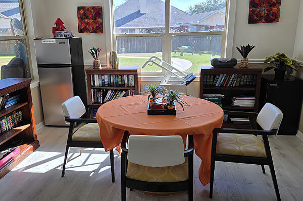 Activities room with a table and four chairs looking out the backyard of a memory care facility in Cypress, Texas